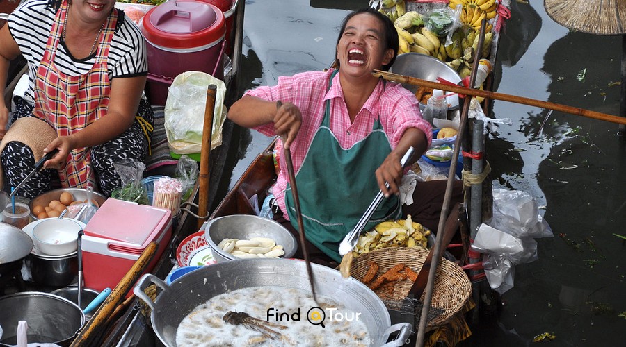 زن تایلندی در حال درست کردن غذا در قایق در بازار شناور دامنئون سادوآک بانکوک