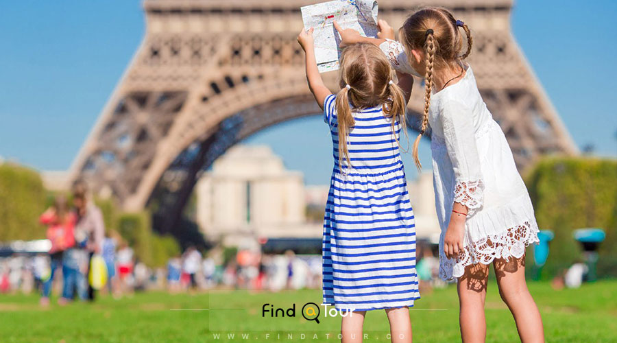 برج ایفل و دو دختربچه با نقشه در حال بازی در سفر به فرانسه